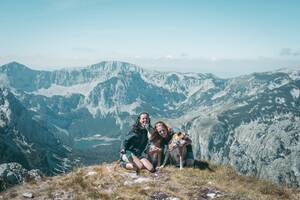 un couple avec deux chiens devant un paysage montagneux avec un lac
