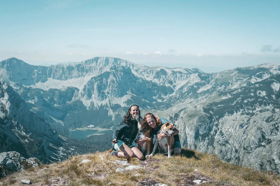 un couple avec deux chiens devant un paysage montagneux avec un lac