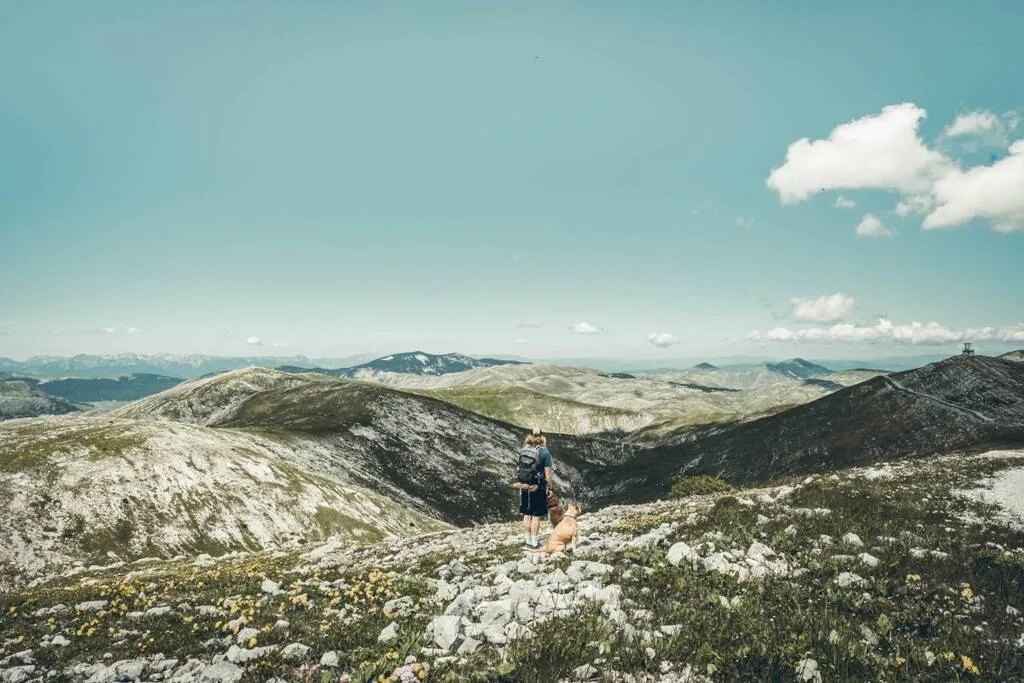 un homme et son chien devant un paysage de montagne à Bjelasnica en Bosnie-Herzégovine