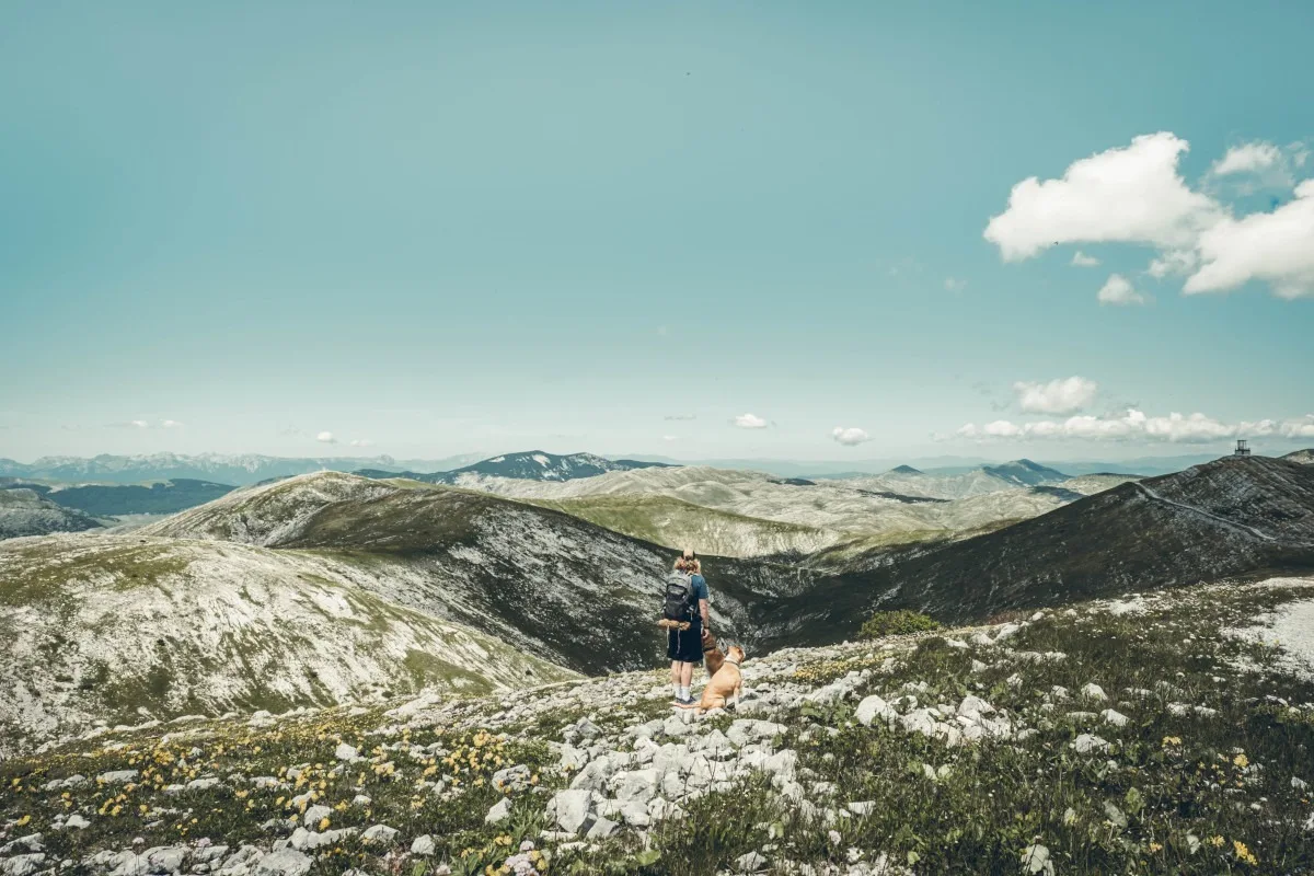 un homme et son chien devant un paysage de montagne à Bjelasnica en Bosnie-Herzégovine