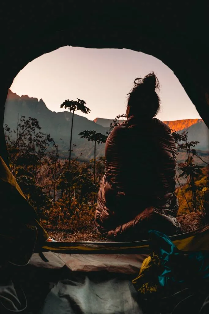 Femme dans son duvet regardant un lever de soleil à Aurère dans le cirque de Mafate.