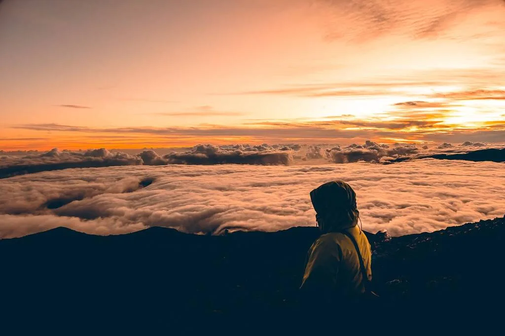 Une personne devant le lever de soleil au piton des Neiges à la Réunion.
