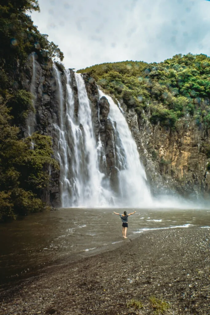 Une femme levant le bras en l'air devant la cascade Niagara sur l'île de la Réunion.