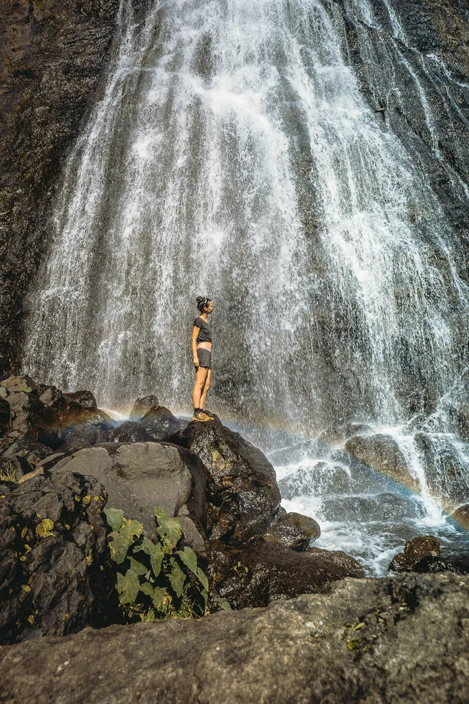 une femme devant la cascade du voile de la mariée avec un petit arc en ciel à la Réunion