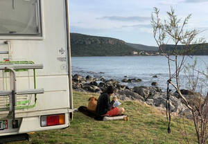 femme avec son chien devant la mer avec son camping-car en Grèce